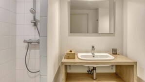 Ein Badezimmer mit Dusche, Waschbecken und Spiegel.