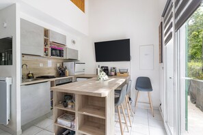 Une cuisine moderne équipée d’un téléviseur à écran plat, de meubles en bois et d’un coin repas avec des tabourets de bar.
