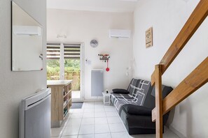 Un espace de vie compact comprenant un canapé, un radiateur, une petite table et un escalier.