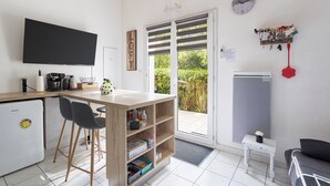 Eine kleine Küche mit Flachbildfernseher, Kaffeemaschine und Kühlschrank.