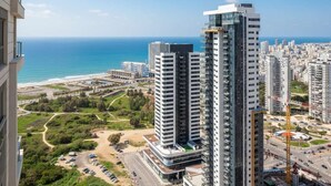 A high-rise building with a view of the sea and a parking area.