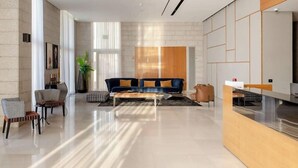 A modern living room with a sofa, chairs, a coffee table, and a reception desk.