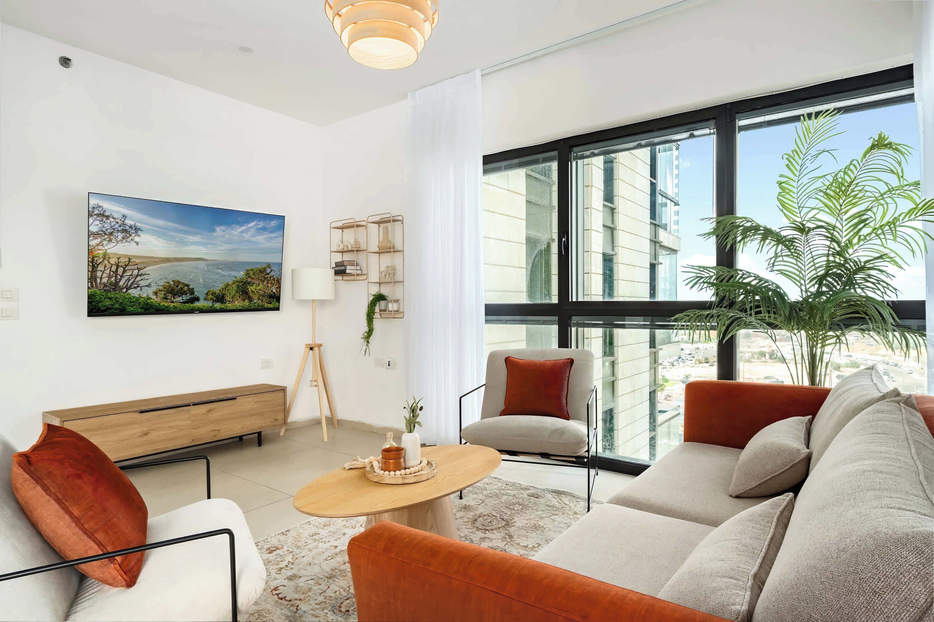 Bright living room frames city views and sea glimpses, creating inviting place to unwind indoors.