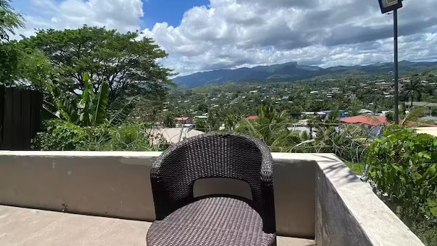 A balcony with wicker chairs and a view of a cityscape and mountains. - Lautoka accommodation (Lautoka)