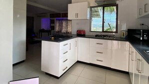 A modern kitchen with white cabinets, a black countertop, and a window with a view. - Lautoka accommodation (Lautoka)