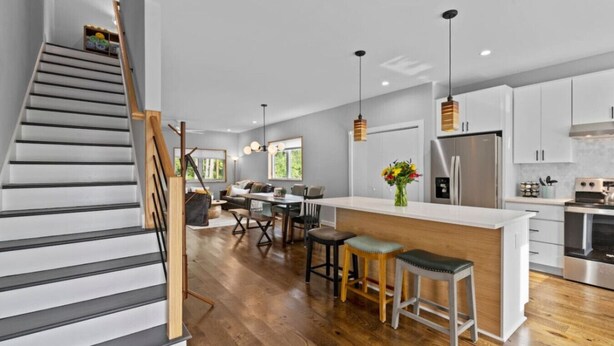 Una cocina moderna con una isla central, suelo de madera y electrodomésticos de acero inoxidable.
