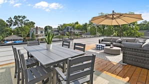 Una terraza en la azotea con una mesa de comedor, sillas, un sofá y una sombrilla.