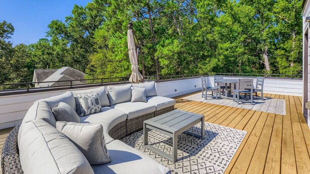 Um terraço no telhado com um sofá modular, uma mesa de jantar e cadeiras.