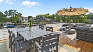 Eine Terrasse mit Tisch, Stühlen und einer Korbschaukel, sowie einem Sonnenschirm.