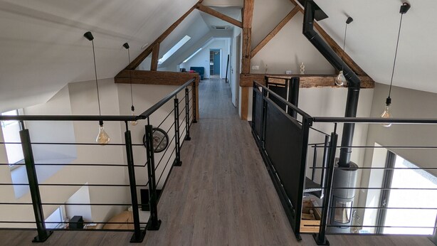 A spacious attic with exposed wooden beams, a central staircase, and a view into the main living area. - Air-Conditioned Cottage with Garden in Tavers (Tavers)