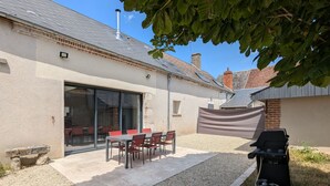 A patio with a table and chairs, a barbecue grill, and a gravel path. - Air-Conditioned Cottage with Garden in Tavers (Tavers)