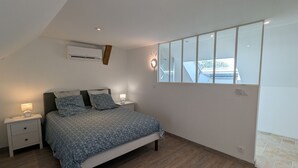 A bedroom with a bed, bedside tables, a wall-mounted air conditioner, and a window with a view of the outside. - Air-Conditioned Cottage with Garden in Tavers (Tavers)