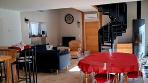 A modern living room with a dining area, a fireplace, and a staircase. - Air-Conditioned Cottage with Garden in Tavers (Tavers)