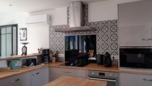 A modern kitchen with a wooden countertop, stainless steel appliances, patterned backsplash, and a built-in oven. - Air-Conditioned Cottage with Garden in Tavers (Tavers)