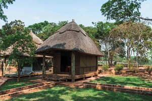 Una estructura con techo de paja, un muelle de madera y un área de descanso cubierta.
