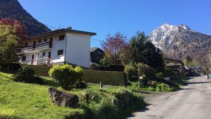 A two-story building with a balcony, surrounded by greenery and a mountain in the background. - Quiet apartment in Cauterets with private parking (Cauterets)