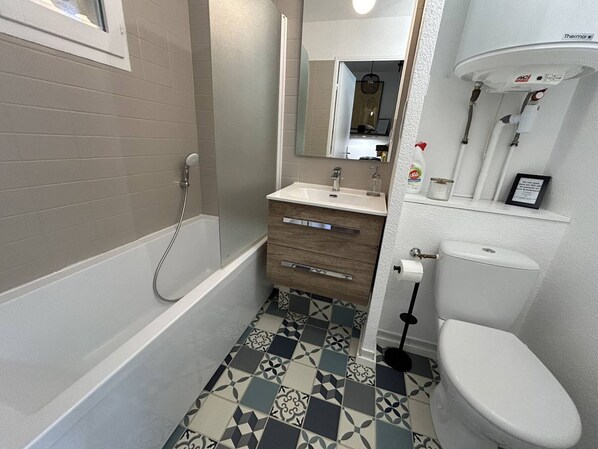 Een badkamer met een bad, toilet, wastafel en spiegel.