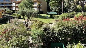 A residential area with a yellow building, a well-maintained garden, and a clear blue sky.