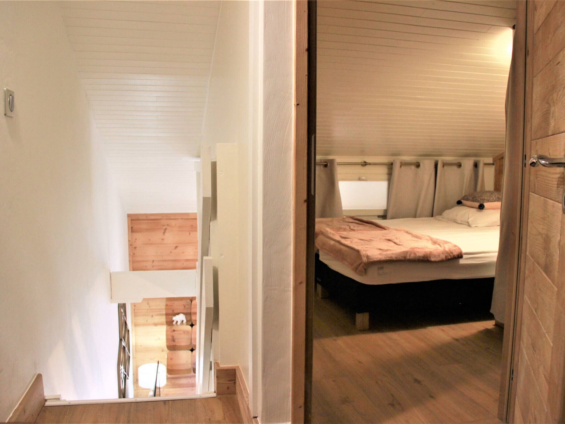 Une chambre à coucher avec un lit, une tête de lit en bois et une fenêtre avec des rideaux.