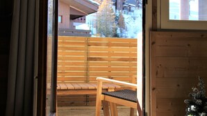 Un banc en bois et une chaise se trouvent dans une pièce dont le mur est également en bois et qui possède une fenêtre.