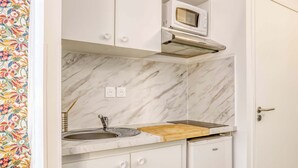 A compact kitchen with a marble backsplash, a microwave, a sink, and a wooden cutting board. - Colivi Studio Tehuana Cosy Gare Annemasse (Annemasse)