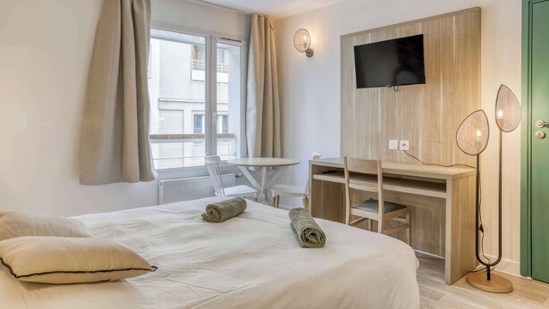 A hotel room with a bed, a desk, a chair, a TV, and a floor lamp. - Colivi Studio Tehuana Cosy Gare Annemasse (Annemasse)