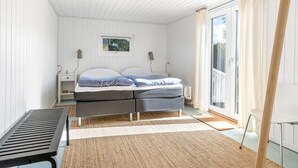 Un dormitorio con cama, mesitas de noche, ventana y vistas al exterior.