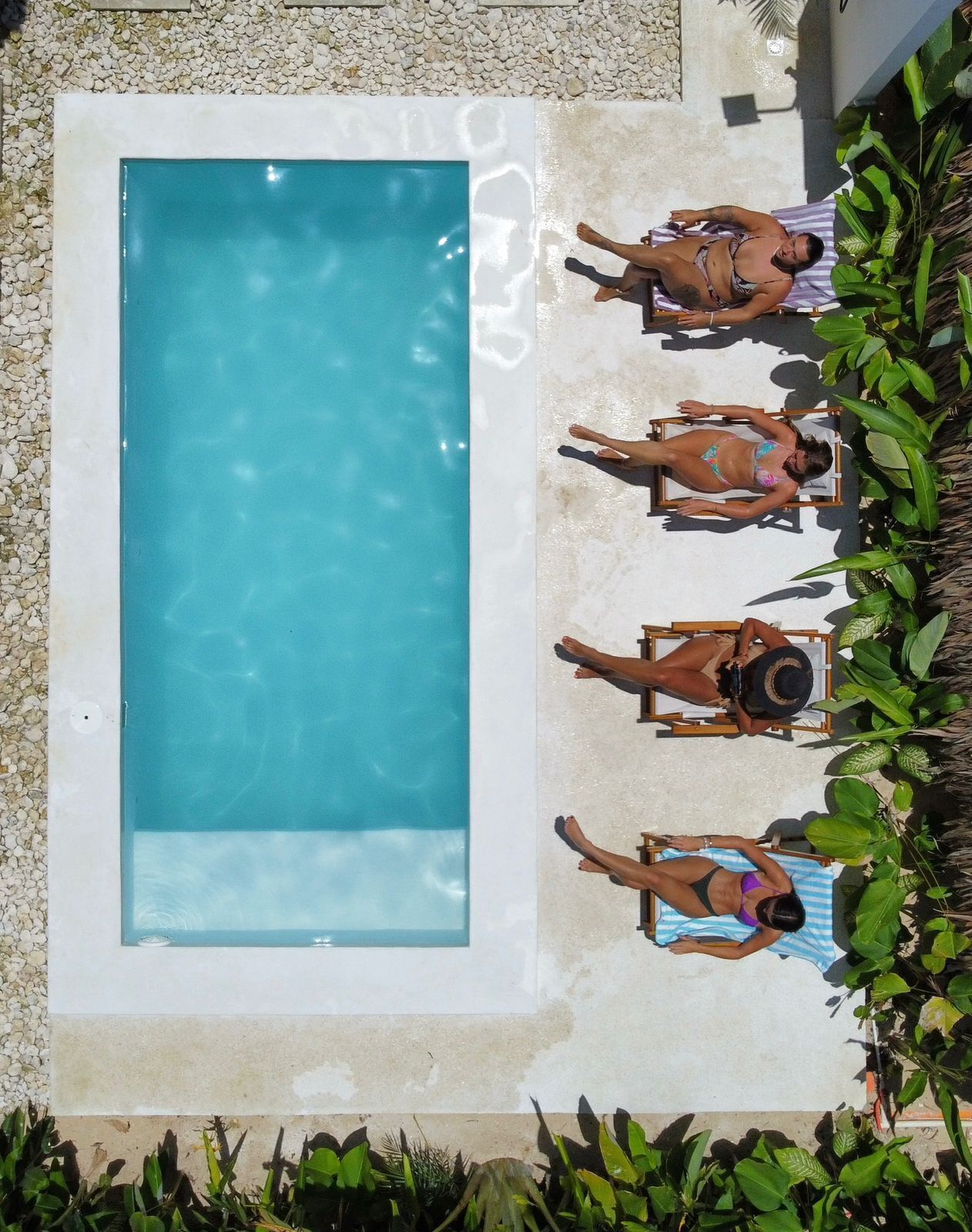 A rectangular pool with four lounge chairs and a tiled deck.
