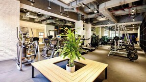 A gym with exercise equipment, a wooden table with a plant, and a white brick wall. - Nice Apartments near Tan Son Nhat Airpot (Ho Chi Minh City)