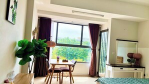 A modern bedroom with a large window, a bed, a desk, and a dining area. - Nice Apartments near Tan Son Nhat Airpot (Ho Chi Minh City)