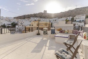 A rooftop terrace with a view of a hillside town, featuring white buildings and a distant castle.