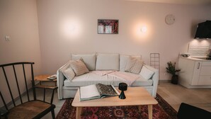 A living room with a light blue sofa, a wooden coffee table, a red patterned rug, a black chair, and a small side table.