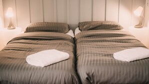 A twin room with two beds, each with a pillow and a folded towel.