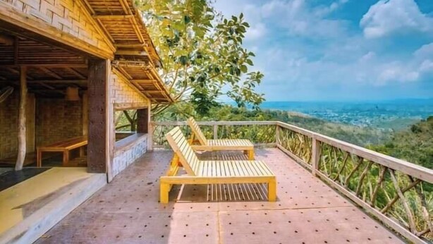 Eine Holzterrasse mit zwei Liegestühlen und Blick auf eine reizvolle Landschaft.