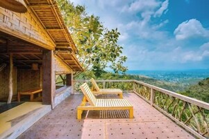 Una terraza de madera con dos sillones de descanso que dan a un paisaje pintoresco.
