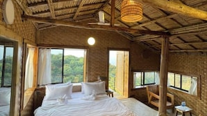 Ein geräumiges Schlafzimmer mit einem großen Bett, zwei mit Vorhängen versehenen Fenstern, einer Holzbalkendecke und einem kleinen Tisch mit Stühlen.
