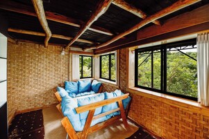 Una habitación con un banco de madera, ventanas amplias y un muro tejido.