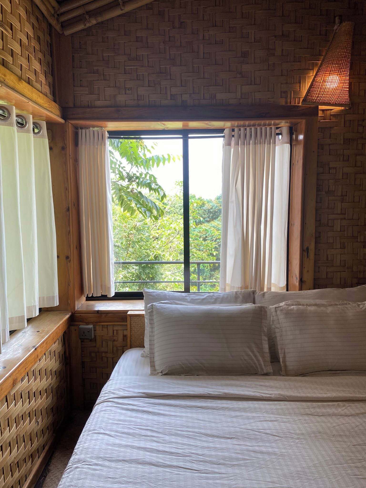 Une chambre avec un grand lit, des murs en bois et une fenêtre avec des rideaux.