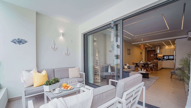 A modern living room with a sofa, coffee table, and a dining area with chairs.