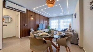A modern dining area with a glass table, wooden chairs, and a contemporary pendant light.