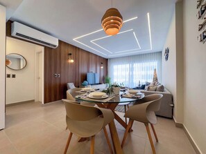 Un comedor moderno con una mesa de vidrio, sillas de madera y una lámpara colgante contemporánea.
