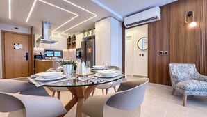 A modern dining area with a glass table, grey chairs, and a wooden ceiling design.