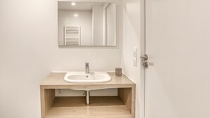 Ein modernes Badezimmer mit einem Holztischchen, einem weißen Waschbecken und einem Spiegel darüber.
