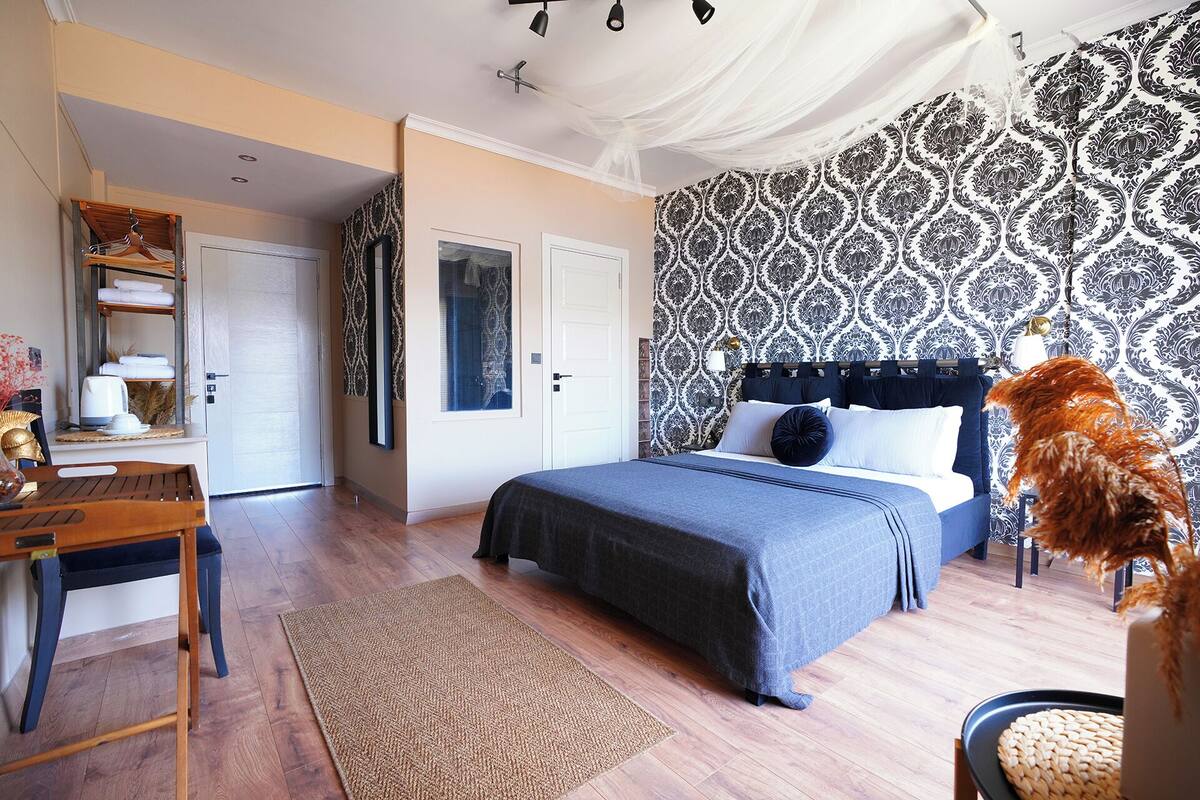 A bedroom with a bed, a desk, a chair, and a window.