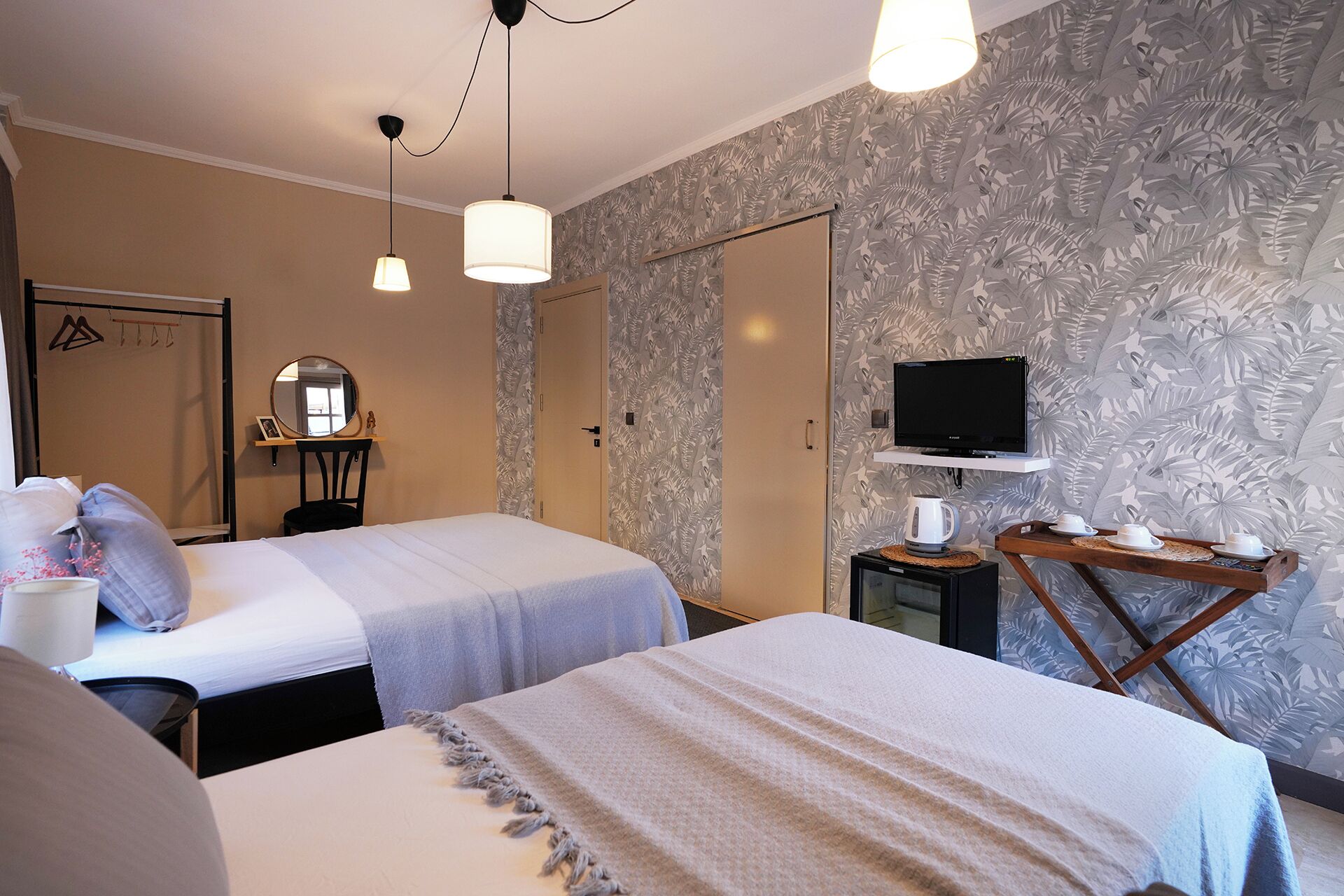 A hotel room with two beds, a television, a coffee maker, and a mirror.