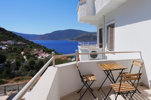 A balcony with a table and chairs, overlooking a coastal view with houses and hills. - Kalkan Ayapa Hotel (Kaş)