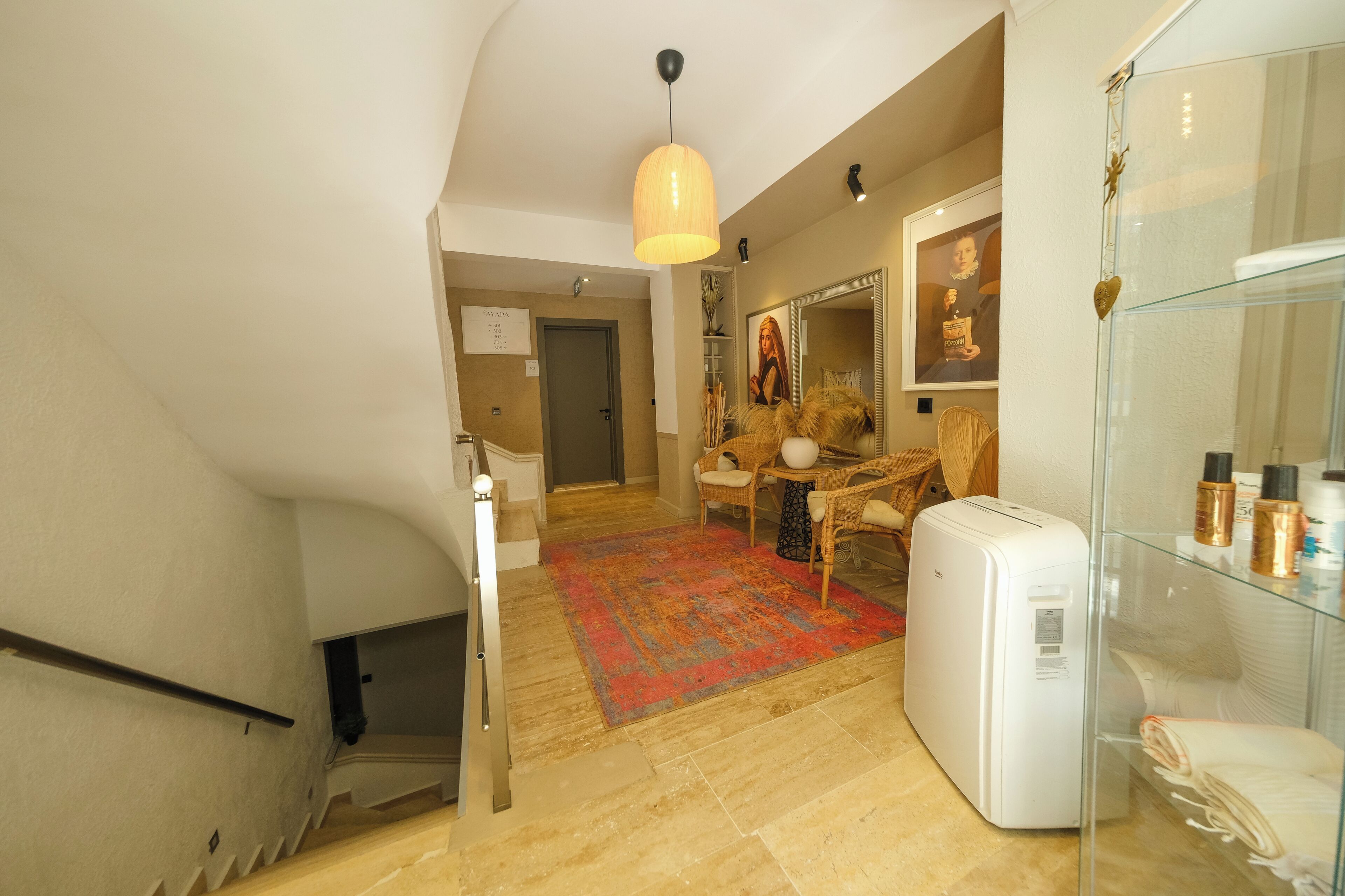 A staircase leading to a living area with a red rug, a white appliance, and a glass display case.