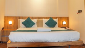 Una cama bien hecha con dos almohadas, una mesita de noche con lámpara y una lámpara de pared.