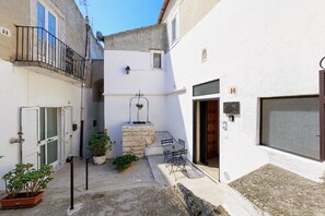 A narrow courtyard with a stone bench, potted plants, and a small table with chairs. - Apartment 'Cantine Cippone Room' with Shared Terrace, Wi-Fi and Air Conditioning (Monte Sant'Angelo)