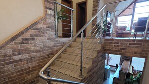 Un intérieur à plusieurs niveaux, doté d’un escalier avec des rampes en métal et des murs en briques.